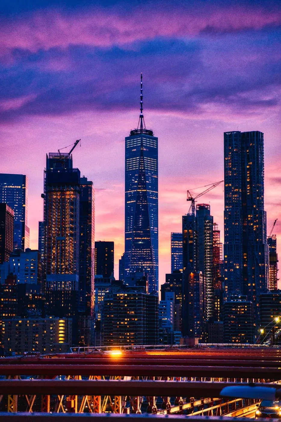 Skyline de Manhattan al atardecer con el One World Trade Center bajo un cielo rosa y morado